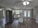 Open kitchen with white cabinets, granite countertops, stainless steel appliances, and wood-look floors at 628 Se Pine Ave, Fort Meade, FL 33841