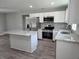 This kitchen features an island, stainless appliances, white cabinets, granite counters, and wood-look flooring at 628 Se Pine Ave, Fort Meade, FL 33841