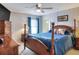 Cozy bedroom with a ceiling fan, patterned wallpaper, wood furnishings, and a comfortable blue bed at 6470 Peppertree Ne Path, Winter Haven, FL 33881