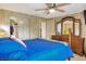 Bright bedroom with a ceiling fan, wood furnishings, closet, and a comfortable blue bed at 6470 Peppertree Ne Path, Winter Haven, FL 33881