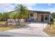 Inviting home showcasing palm tree landscaping, a covered carport, and a charming front patio area at 6470 Peppertree Ne Path, Winter Haven, FL 33881