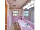 Pink-tiled bathroom featuring retro accents, a long vanity, and a bathtub with a shower curtain at 780 Oleander Se Dr, Winter Haven, FL 33880