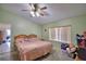 Well-lit bedroom featuring a comfortable bed, window, ceiling fan, and lots of personal items and color at 780 Oleander Se Dr, Winter Haven, FL 33880