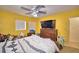 Sunny yellow bedroom featuring a mounted television and window bringing in natural light at 780 Oleander Se Dr, Winter Haven, FL 33880