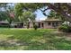Charming single-story home with a well-manicured lawn, mature trees, and a covered parking area at 105 Leslie Ave, Winter Haven, FL 33880