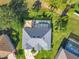 Aerial view of the property featuring a large gray roof, a screened pool area, landscaping, and the driveway at 123 Evergreen Dr, Auburndale, FL 33823