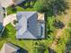 Aerial view of the property featuring a large gray roof, a screened pool area, landscaping, and the driveway at 123 Evergreen Dr, Auburndale, FL 33823