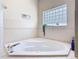 Corner bathtub with tile surround and block window for natural light and privacy at 123 Evergreen Dr, Auburndale, FL 33823