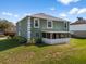 Back exterior view of a green two-story home with a screened in porch and green lawn at 1800 Emily Dr, Winter Haven, FL 33884