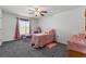 Bright bedroom featuring gray carpeting, a ceiling fan, and a large window at 1800 Emily Dr, Winter Haven, FL 33884