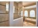 Elegant bathroom with a glass-enclosed shower and a luxurious soaking tub beneath arch windows, offering a spa-like experience at 2340 Pinehurst Ct, Davenport, FL 33837
