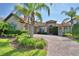 Inviting front exterior featuring lush landscaping, a brick driveway, and a charming entrance at 2340 Pinehurst Ct, Davenport, FL 33837