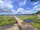Inviting wooden dock extends into a tranquil lily pad-covered lake under a beautiful sky at 255 Lake Link Rd, Winter Haven, FL 33884