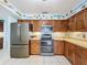 Well-lit kitchen showcasing stainless steel appliances, tiled floors, and wood cabinets with ample storage space at 255 Lake Link Rd, Winter Haven, FL 33884