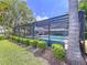 Enclosed pool with green vegetation and view of the home and blue umbrella inside screened enclosure at 255 Lake Link Rd, Winter Haven, FL 33884