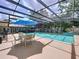 Enclosed pool area featuring a patio dining set and lush landscaping at 255 Lake Link Rd, Winter Haven, FL 33884