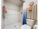 White tiled shower over toilet featuring a blue ombre curtain and multiple towel racks at 255 Lake Link Rd, Winter Haven, FL 33884
