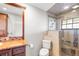 Bathroom featuring a tiled shower with glass door, toilet, and vanity with a dark wood cabinet at 2731 State Road 557, Lake Alfred, FL 33850