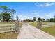 Long driveway leading to a charming two-story home, framed by a white fence and horse statues at 2731 State Road 557, Lake Alfred, FL 33850