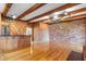 Spacious living room featuring exposed brick wall, wood paneling, wood beams, and hardwood floors at 2731 State Road 557, Lake Alfred, FL 33850