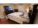 Well-lit bedroom with dark wood bed frame, TV, and dresser, and wood flooring at 3828 Eloise Estates Ct, Winter Haven, FL 33881