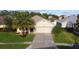 Inviting single-story home featuring a lush green lawn and a two-car garage, enhanced by mature palm trees at 3828 Eloise Estates Ct, Winter Haven, FL 33881