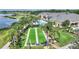 Aerial view of a pristine bocce ball court near clubhouse and a sparkling pool surrounded by lush landscaping and swaying palms at 4175 Muirfield Loop, Lake Wales, FL 33859