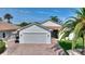 Charming single-story home with a brick driveway, two-car garage and palm trees at 4175 Muirfield Loop, Lake Wales, FL 33859