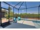 Under a screened-in enclosure, a seating area by an in-ground pool creates an inviting backyard oasis at 4175 Muirfield Loop, Lake Wales, FL 33859