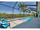 Under a screened-in enclosure, a glistening in-ground pool with blue accents and ample seating at 4175 Muirfield Loop, Lake Wales, FL 33859