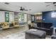 Bright living room with gray sofa, two yellow chairs, large windows with shutter blinds, and wood-look flooring at 418 North Rd, Lakeland, FL 33809