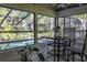 Screened-in porch with a table and chairs overlooking a refreshing pool area with mature trees beyond at 418 North Rd, Lakeland, FL 33809