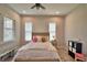 Cozy bedroom featuring a full-size bed, two windows with blinds, and light wood-look flooring at 445 Waterfern Trail Dr, Auburndale, FL 33823