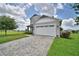 Well-maintained home with a spacious driveway, lush green lawn, and manicured landscaping at 445 Waterfern Trail Dr, Auburndale, FL 33823