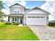 Charming two-story home with a well-manicured lawn and inviting covered front porch with seating at 445 Waterfern Trail Dr, Auburndale, FL 33823