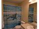 Well-lit bathroom featuring a vanity sink, toilet, and shower/tub with a vibrant turtle themed curtain at 4488 Turnberry Ln, Lake Wales, FL 33859