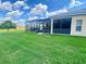 Lush green backyard featuring a screened lanai with patio furniture, ideal for outdoor living and entertaining at 5005 Pebble Beach Blvd, Winter Haven, FL 33884