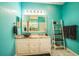 Turquoise bathroom featuring white cabinets, vessel sink, marble countertop, and decorative ladder shelf at 5005 Pebble Beach Blvd, Winter Haven, FL 33884