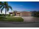 Inviting single-story home at dusk features a decorative fountain, manicured lawn, and a brick-paved driveway leading to a two-car garage at 5005 Pebble Beach Blvd, Winter Haven, FL 33884