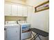 Bright laundry room with white cabinets, washer, dryer, and ironing board at 5005 Pebble Beach Blvd, Winter Haven, FL 33884