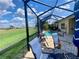 Screened in patio features seating area overlooking pool and golf course at 5005 Pebble Beach Blvd, Winter Haven, FL 33884