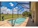 Inviting screened-in pool area with clear blue water, brick-paved deck, and views of the lush green backyard and surrounding landscape at 5005 Pebble Beach Blvd, Winter Haven, FL 33884