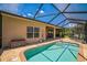 Screened-in pool area with a brick-paved deck, featuring clear blue water and a comfortable lounge area for relaxation at 5005 Pebble Beach Blvd, Winter Haven, FL 33884