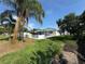 Exterior view of the home from the yard, featuring a lush lawn, tall palm trees, and large pool at 502 Canal Dr, Lake Wales, FL 33859