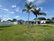 Charming single-story home featuring lush green lawn, two palm trees, and a covered carport on a sunny day at 502 Canal Dr, Lake Wales, FL 33859