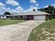 Single-story brick house with a long driveway, attached garage, and green lawn under a partly cloudy sky at 504 W 7Th St, Frostproof, FL 33843