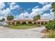 Exterior view of the clubhouse with arched windows, palm trees, and an American flag waving at 5102 Village Ct # E-2, Lake Wales, FL 33898