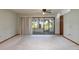 A bright living room with access to a screened lanai through sliding glass doors, and light-colored carpet at 5102 Village Ct # E-2, Lake Wales, FL 33898