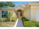 Home's front entrance with a covered porch, decorative plants, and a well-lit walkway at 630 Heather Glen Loop, Winter Haven, FL 33884
