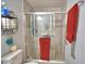 Bright bathroom features a glass-enclosed shower, neutral tiling, and convenient storage shelves at 879 Orleans Dr, Eagle Lake, FL 33839
